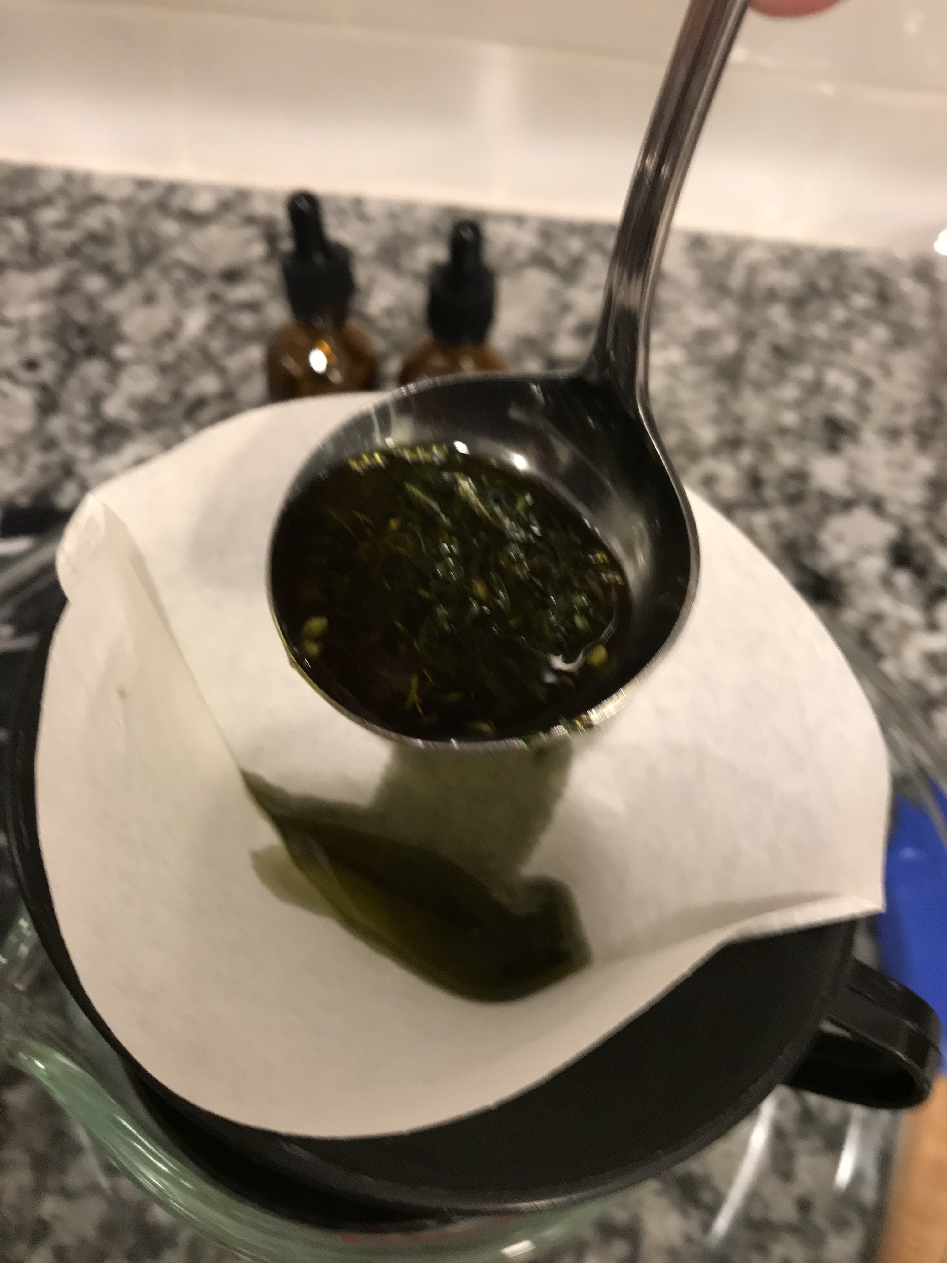Pour the infused coconut oil through the filter paper. Use a ladle to spoon the cannabis and coconut oil through the filter, if your crockpot is too heavy to hold.
